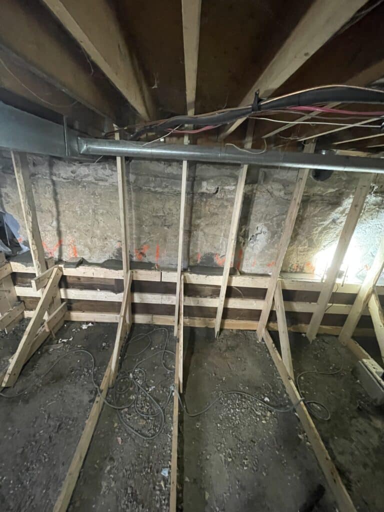 Installer checking window well depth and foundation cut for accurate egress fit, Installer measuring foundation opening for precise egress window fit and drainage