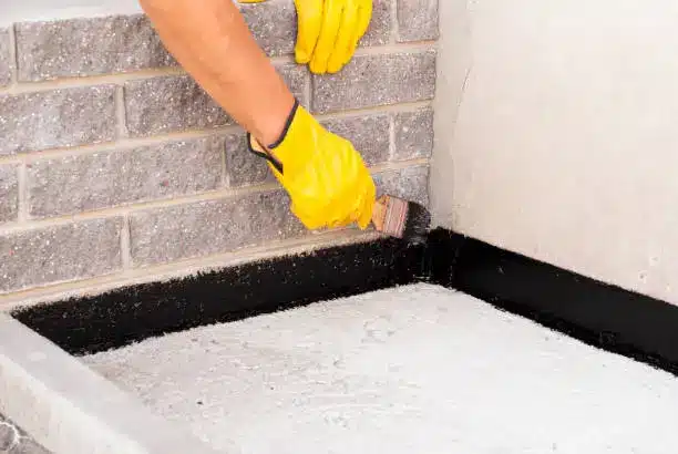 Basement Waterproofing in McArthurs Mills - ON as a specialist examines seepage along a basement wall, Basement Waterproofing in McDonalds Corners - ON as a technician checks a damp foundation wall for seepage